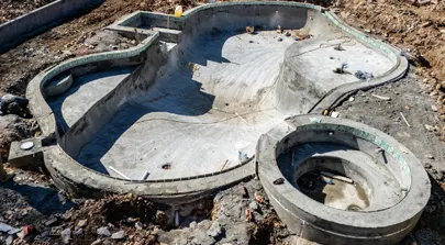 Inground concrete pool under construction with circular spa section.