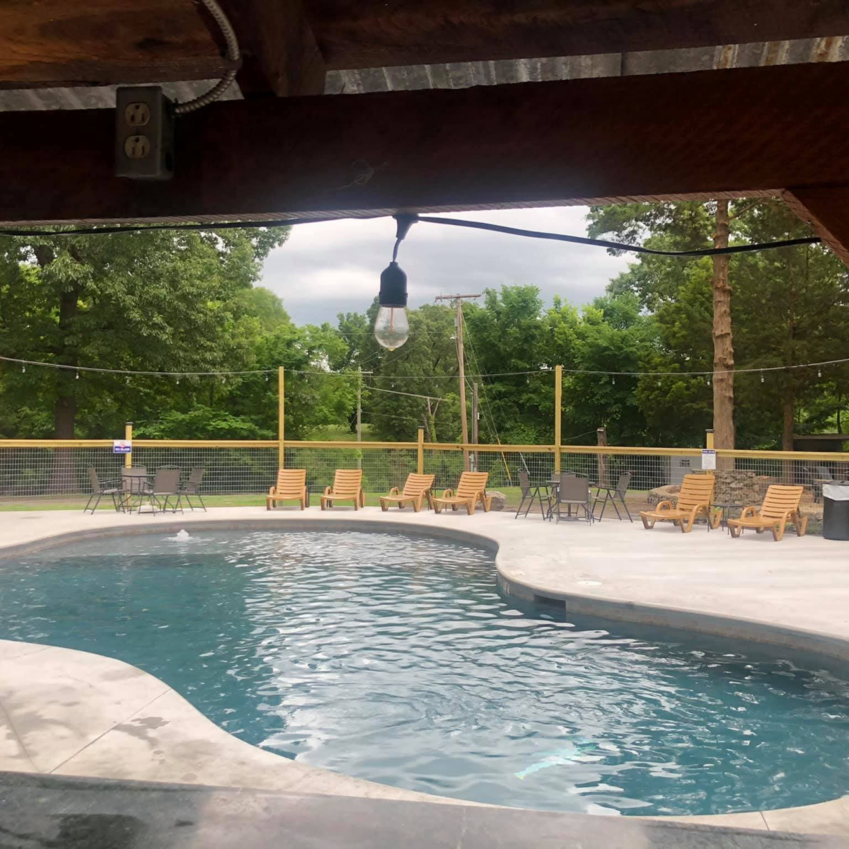 Outdoor pool area with deck chairs and surrounding trees.